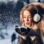 woman blowing snow on her hands