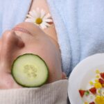 woman wearing blue robe lying with cucumber on eye