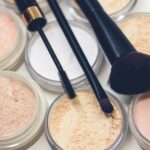 three makeup brushes on top of compact powders